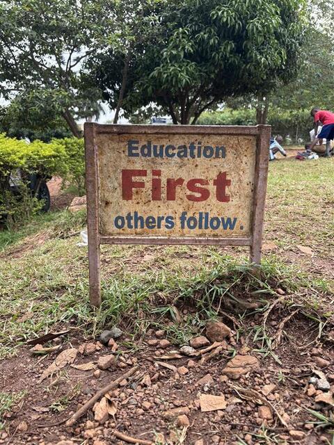 A schoolyard sign reads “Education First, others follow.”